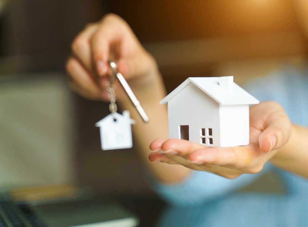 A Person Is Holding A Model House And Keys In Their Hands — Anytime Conveyancing In Wingham, NSW