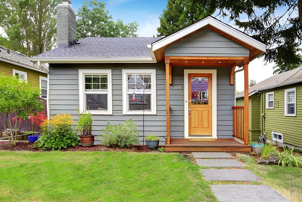 A Small Gray House With A Porch And A Wooden Door — Anytime Conveyancing In Wingham, NSW