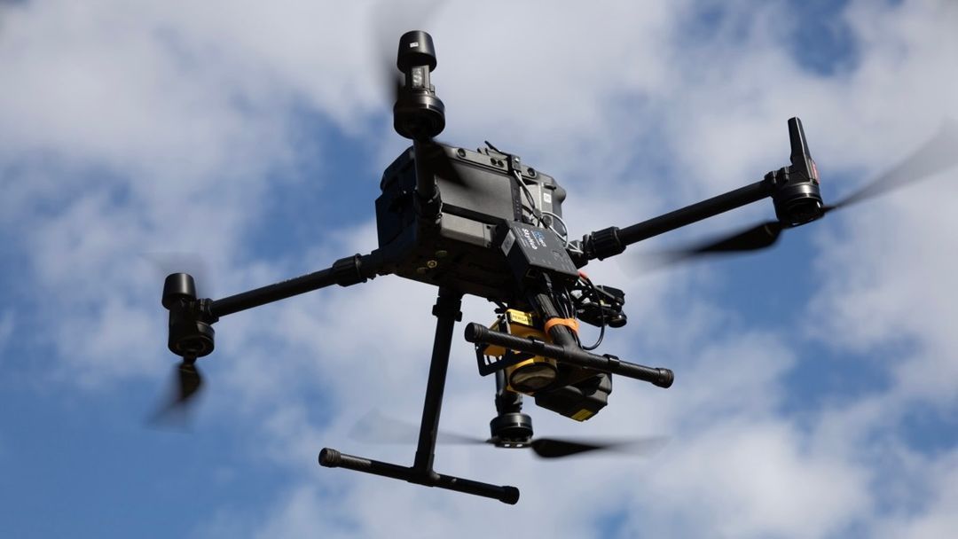 A drone is flying in the sky with a camera attached to it.