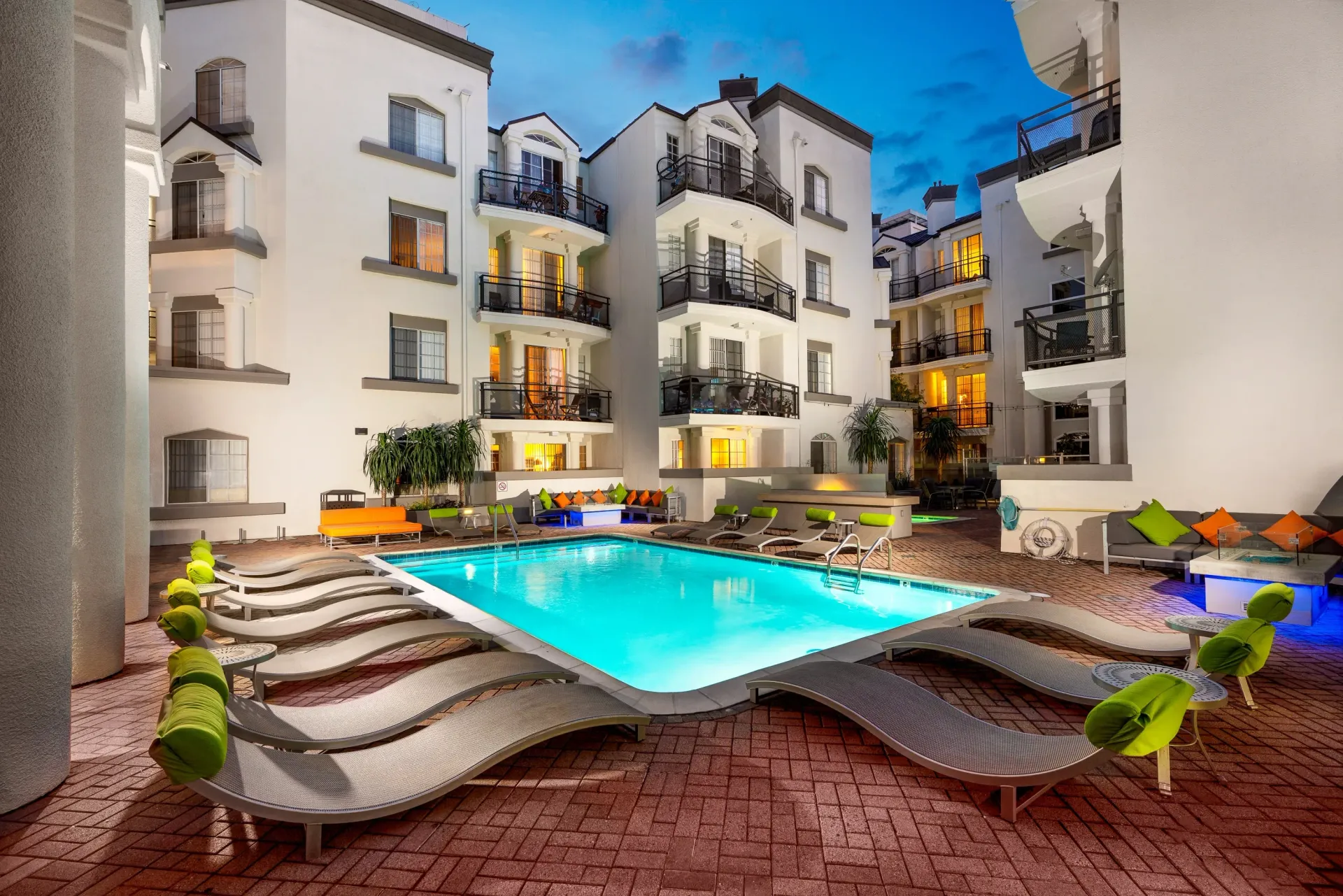 Luxurious swimming pool and lounge area at apartment complex at dusk.