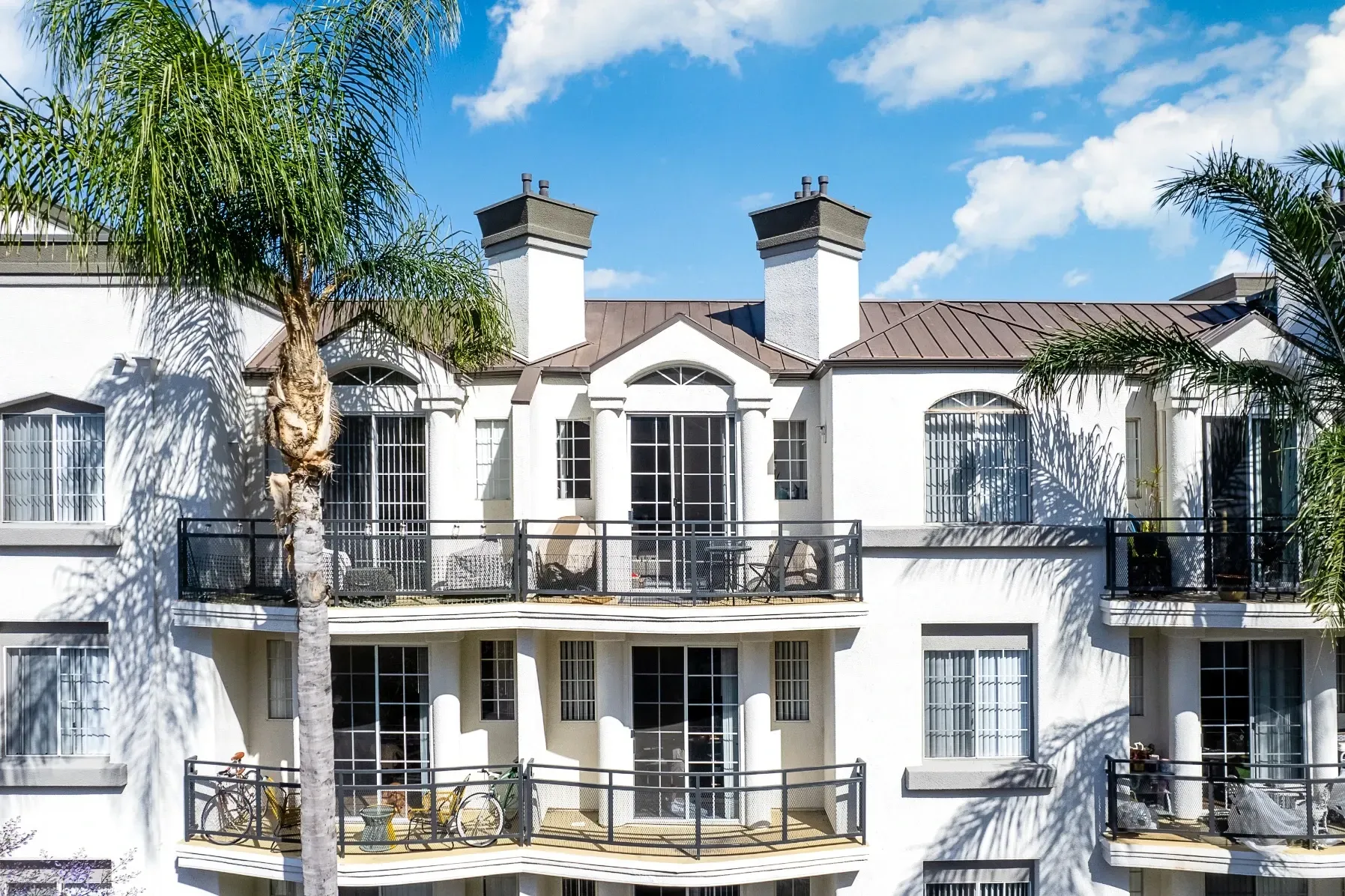 Exterior of apartment building with balconies and palm trees