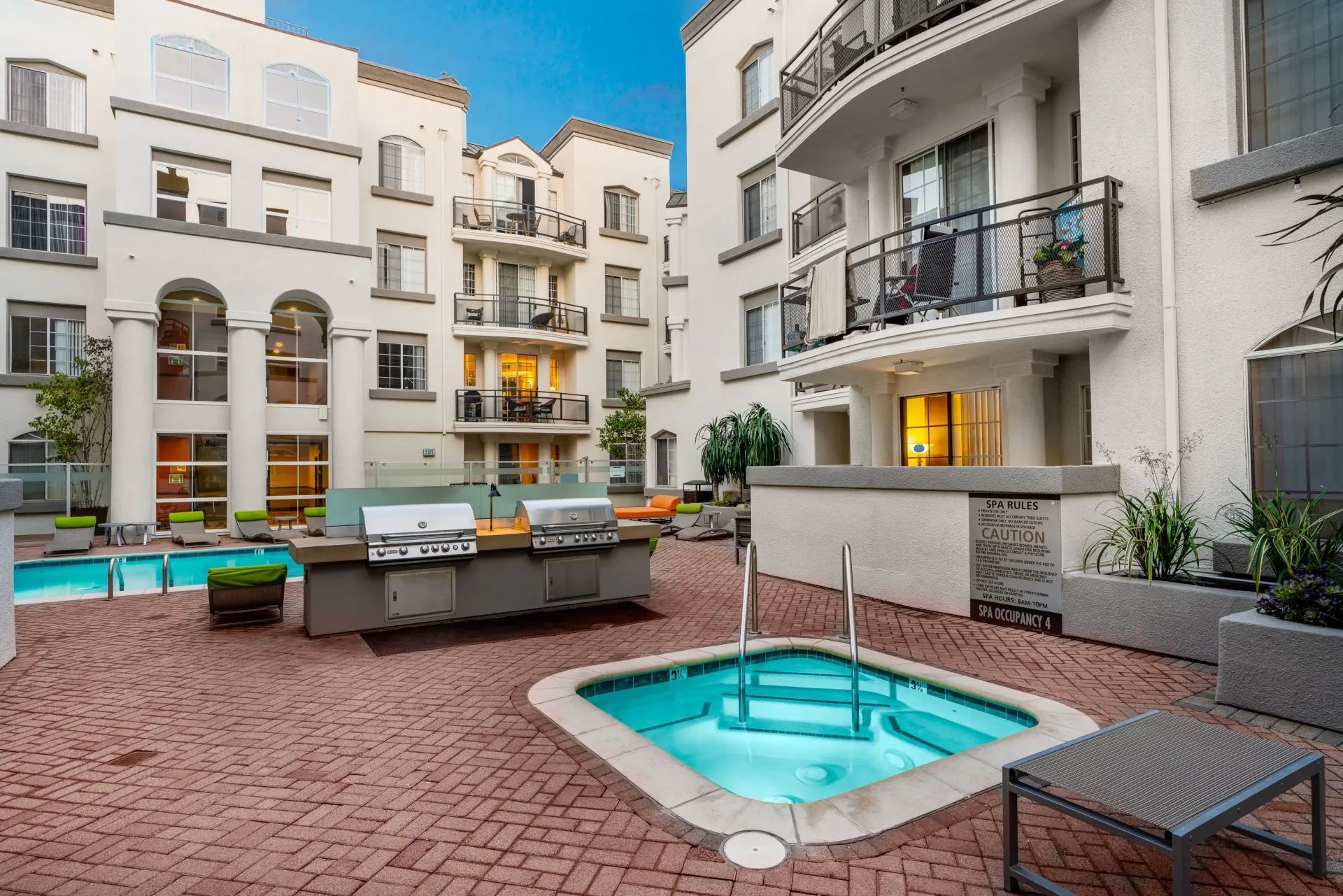 Courtyard with a pool, hot tub, and outdoor grilling station.