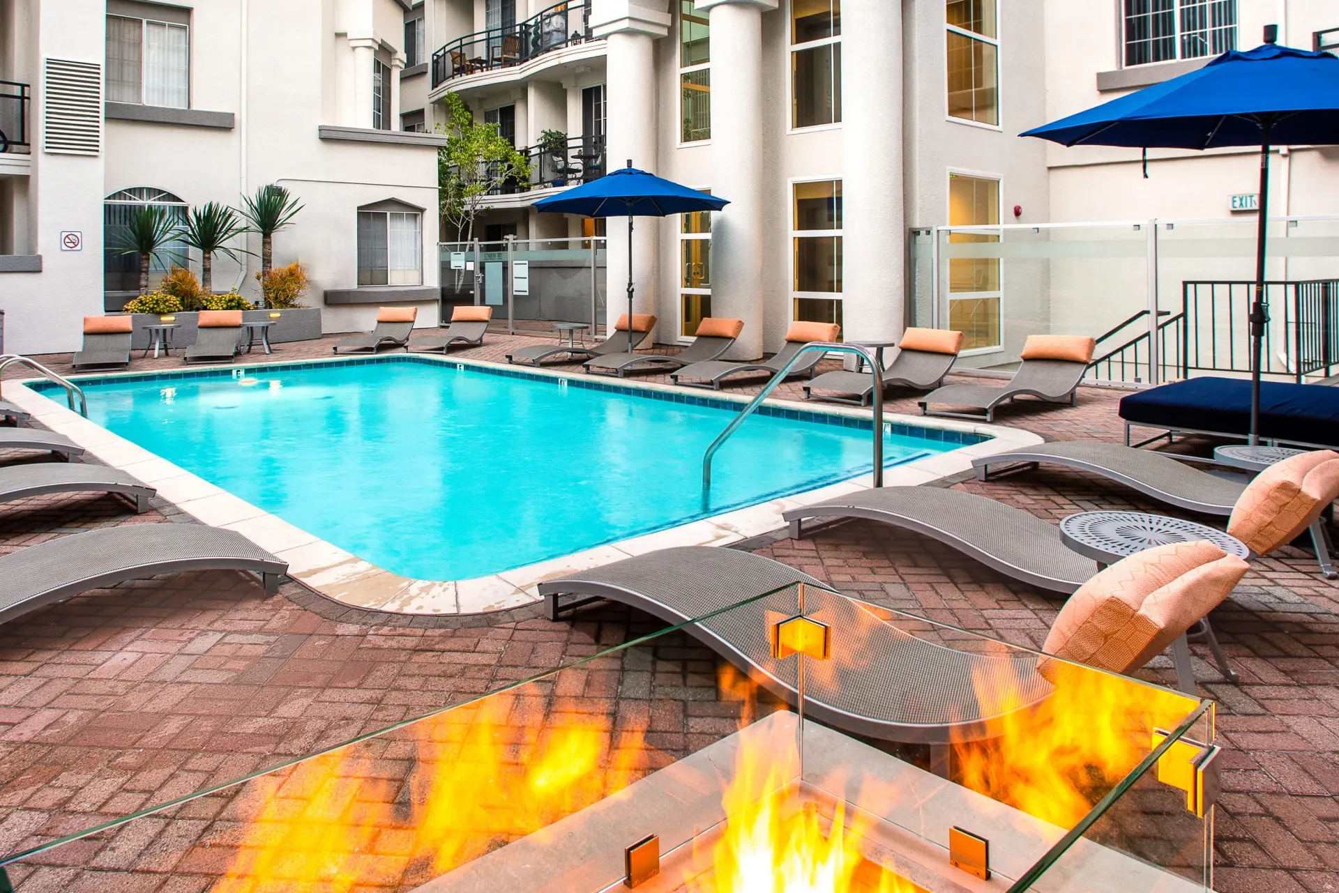 Outdoor swimming pool with lounge chairs and a fire pit.