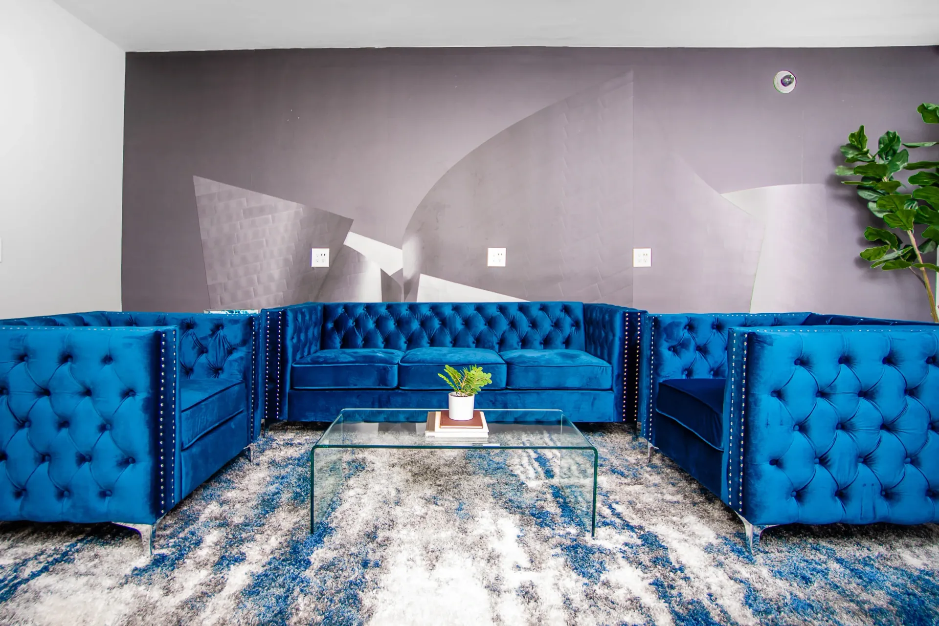Modern lounge area with plush blue tufted sofas and a glass coffee table.