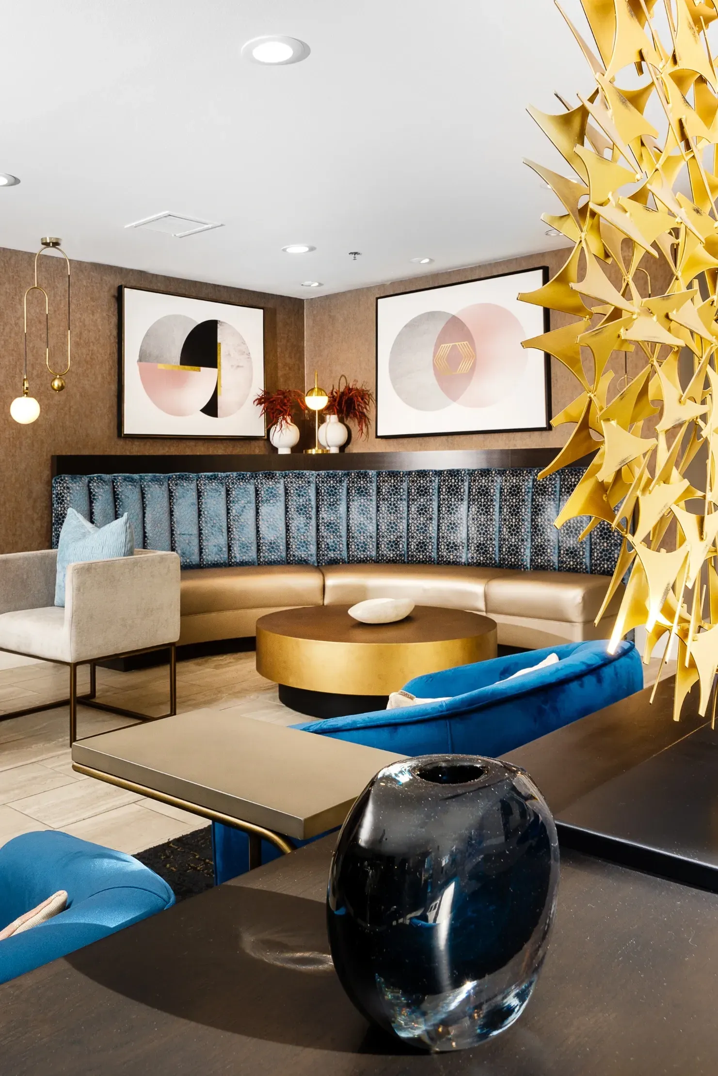 Modern lounge area with curved seating, abstract art, and metallic decor.