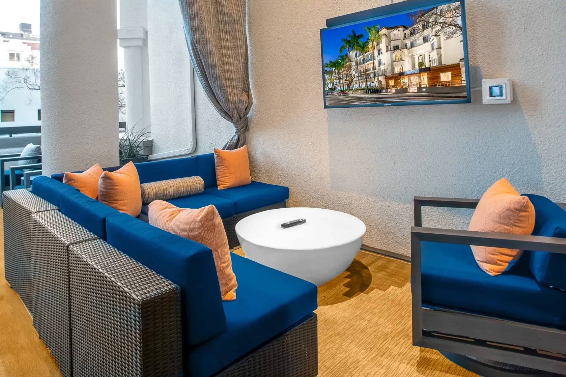 Outdoor lounge area with blue sectional sofas, orange pillows, and a white coffee table.