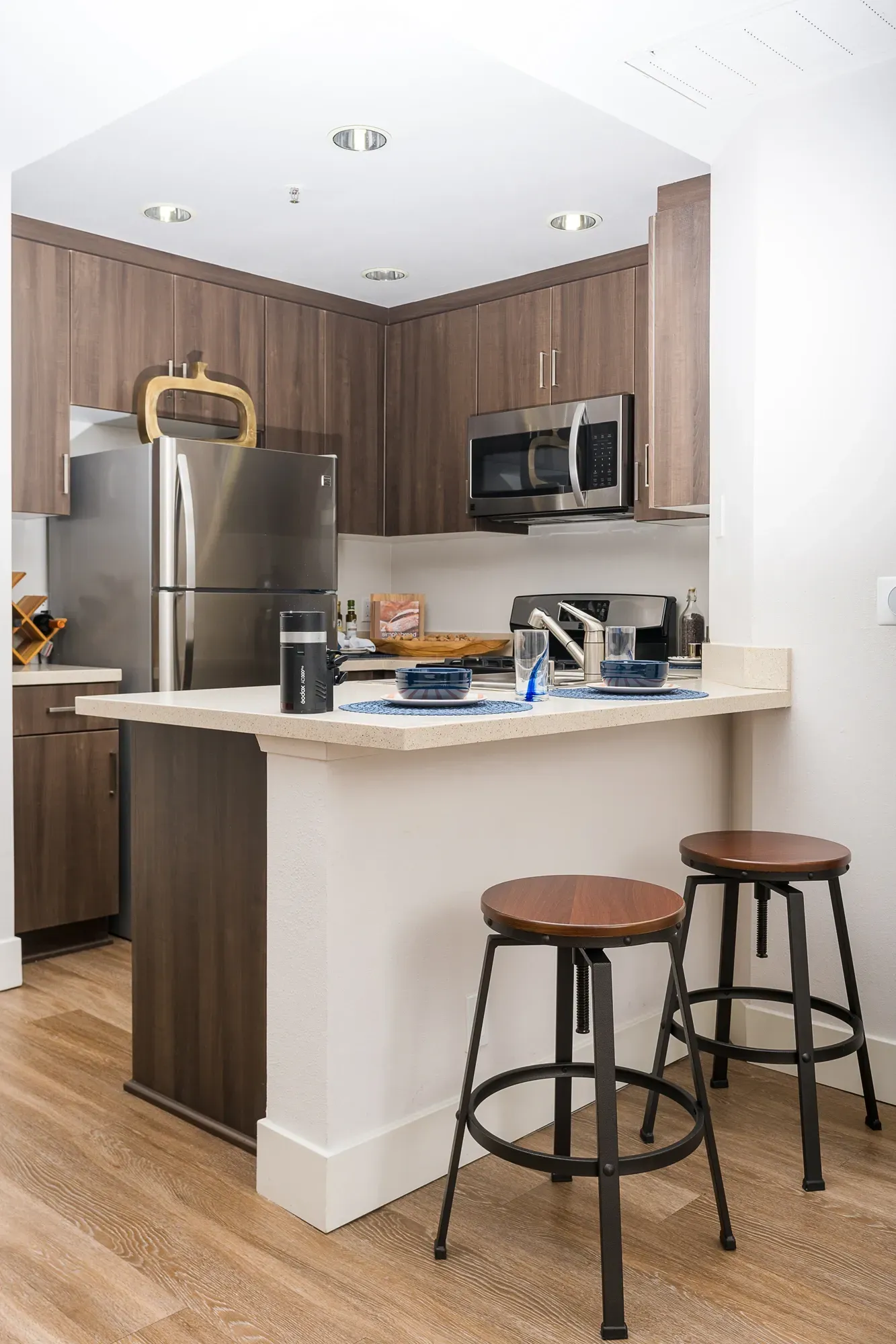 Modern kitchen with stainless steel appliances and breakfast bar with stools.