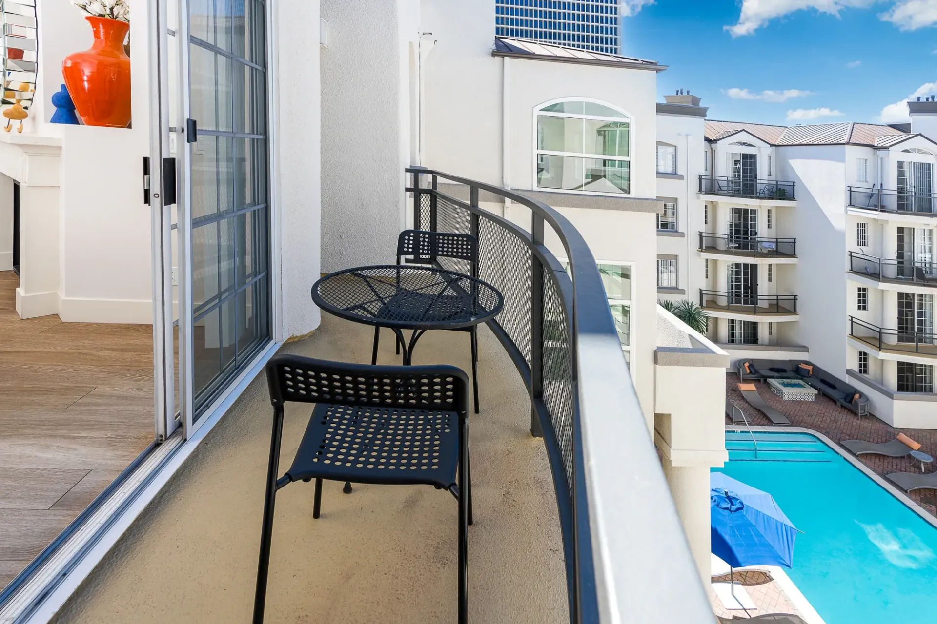 Balcony with seating overlooking a courtyard and pool.