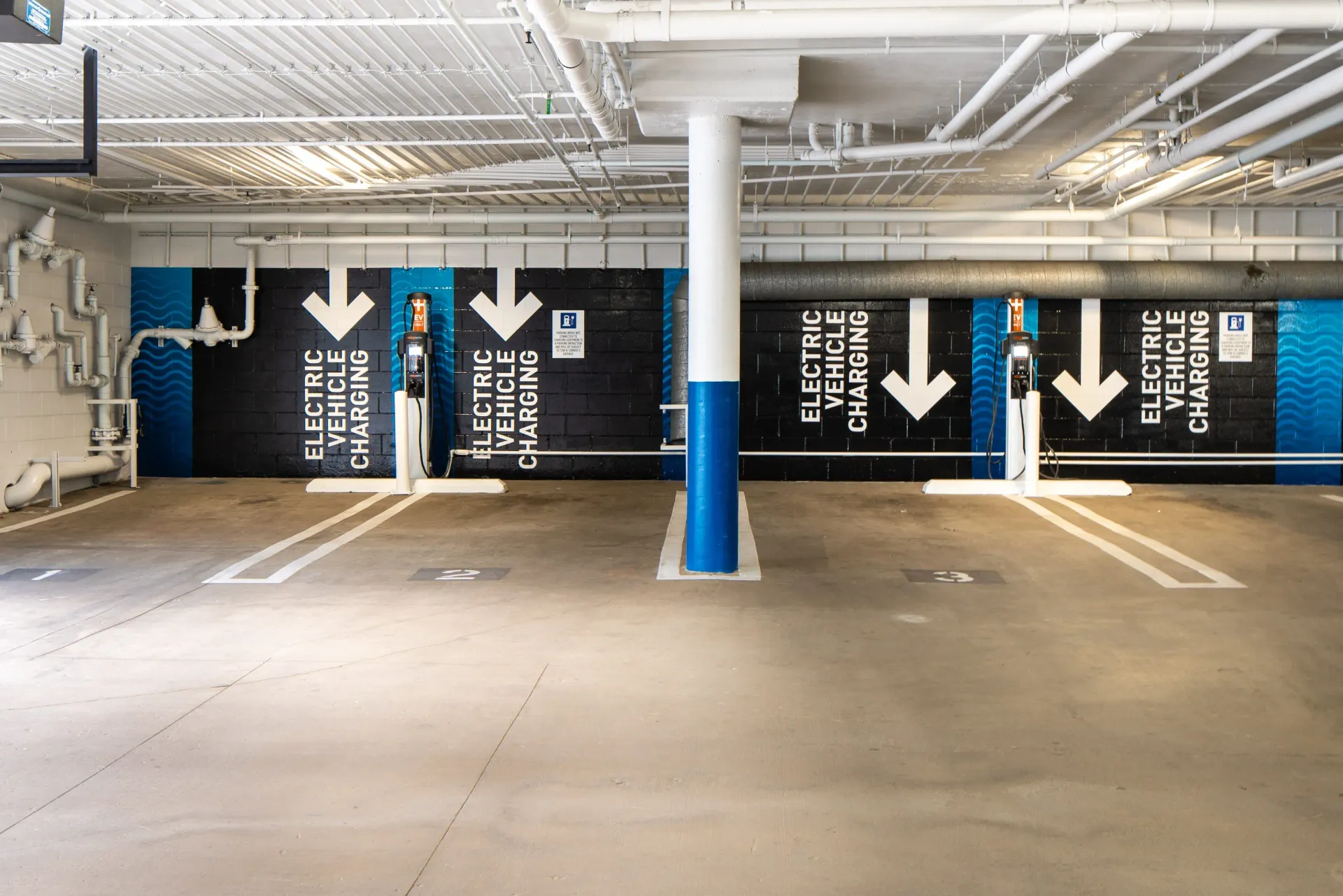Electric vehicle charging stations in a parking garage with directional arrows.