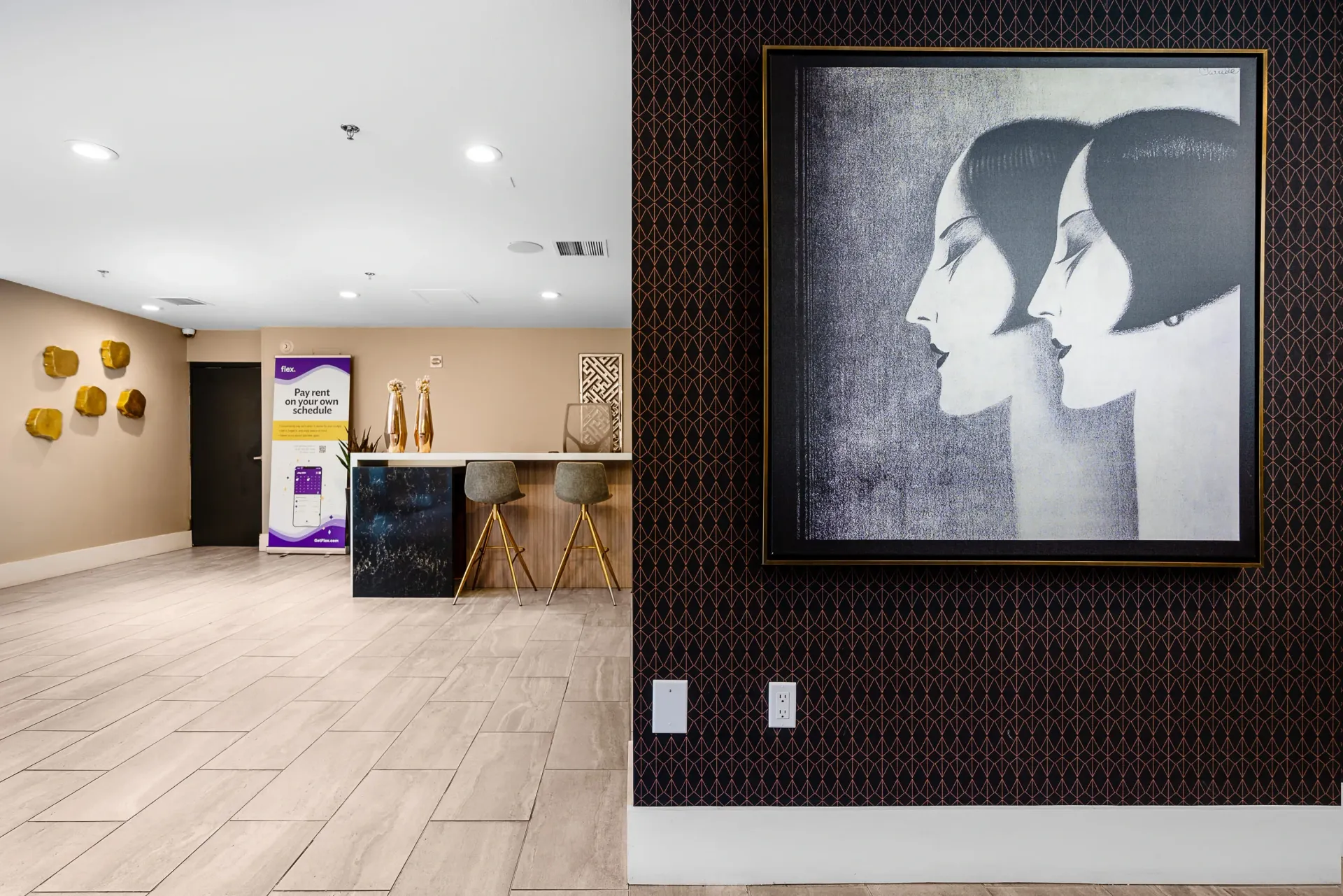 Modern reception area with a bar, stools, and artwork.