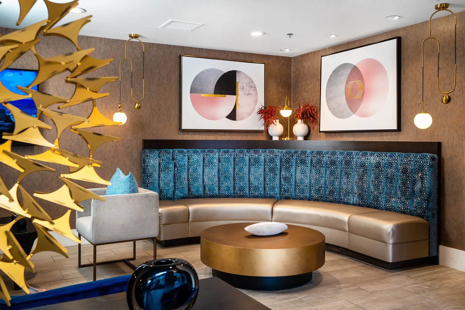 Modern seating area with a curved blue upholstered sofa and gold coffee table.