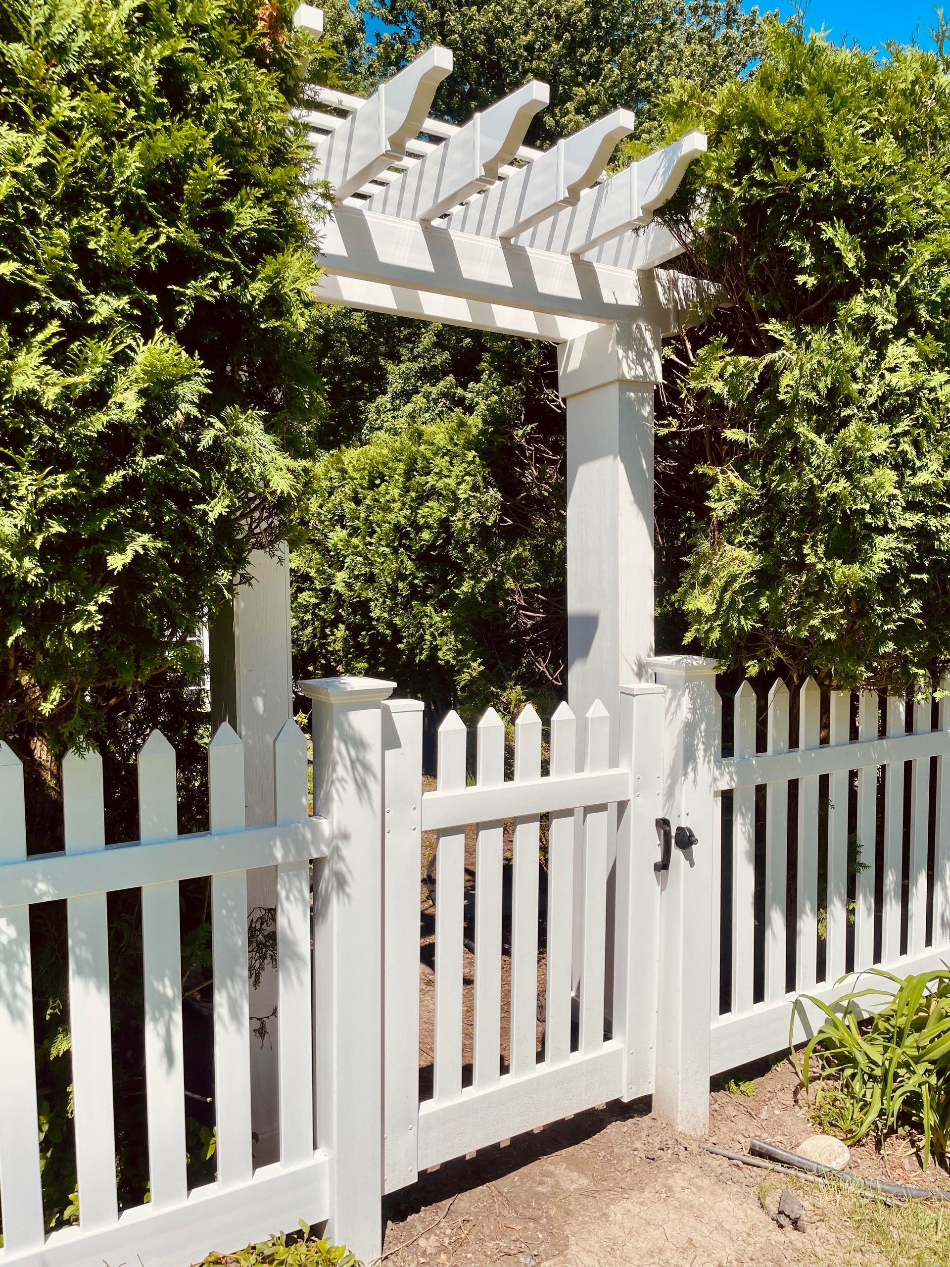 A white picket fence with a gate and a pergola