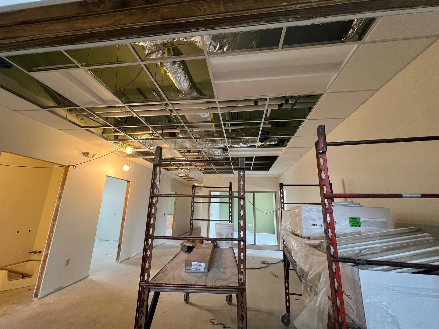 Interior renovation with scaffolding, exposed ceiling beams, and drywall in progress