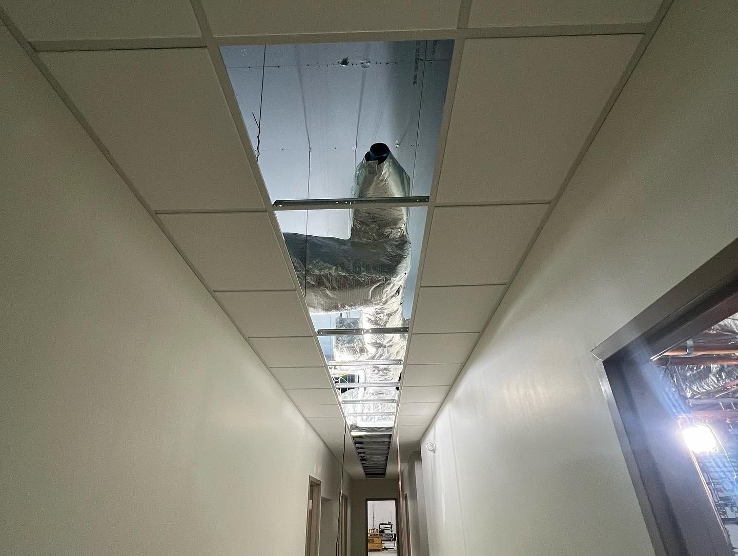 Person hanging upside down through a damaged ceiling in a narrow hallway