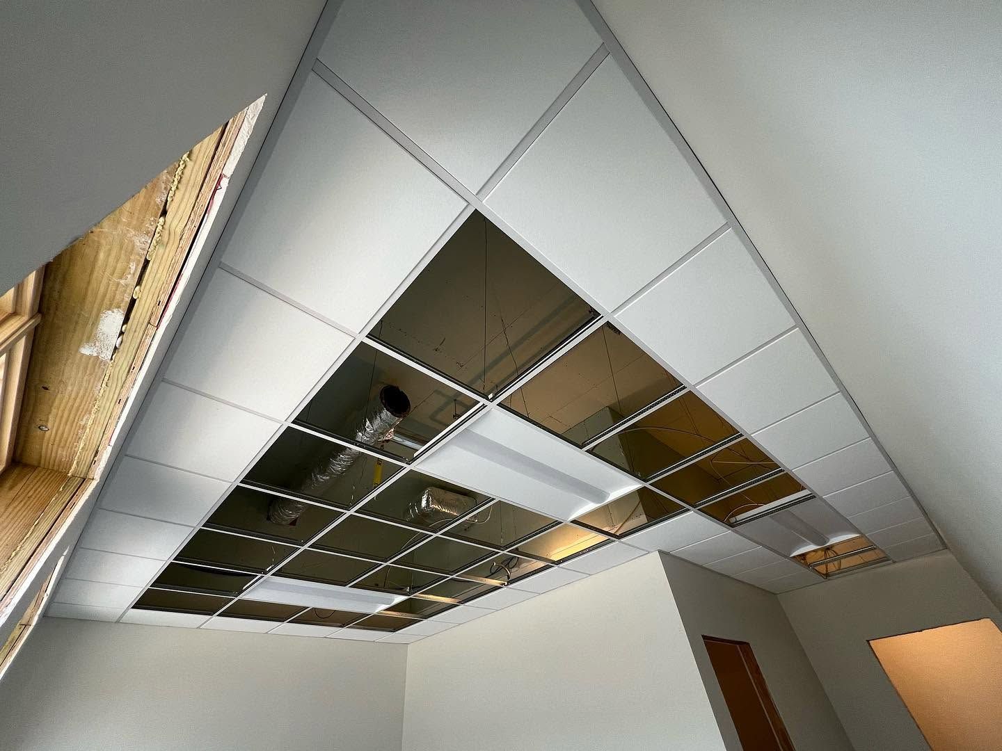 Damaged office ceiling with missing tiles, exposed grid, and hanging fluorescent lights