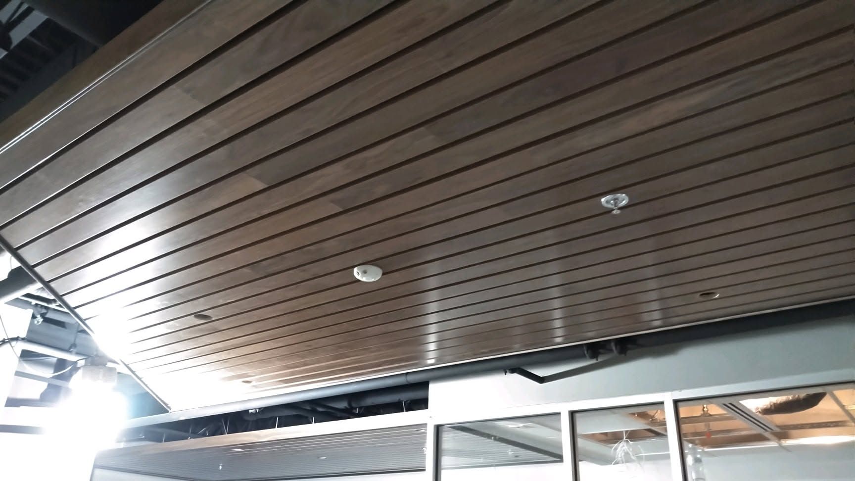 Wood-paneled ceiling with recessed lights above a storefront or patio area