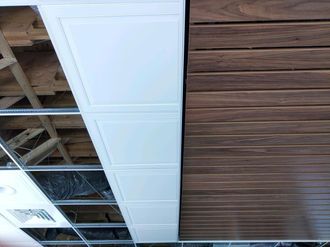 Ceiling with white acoustic tiles, exposed grid, and a wood-paneled section under construction