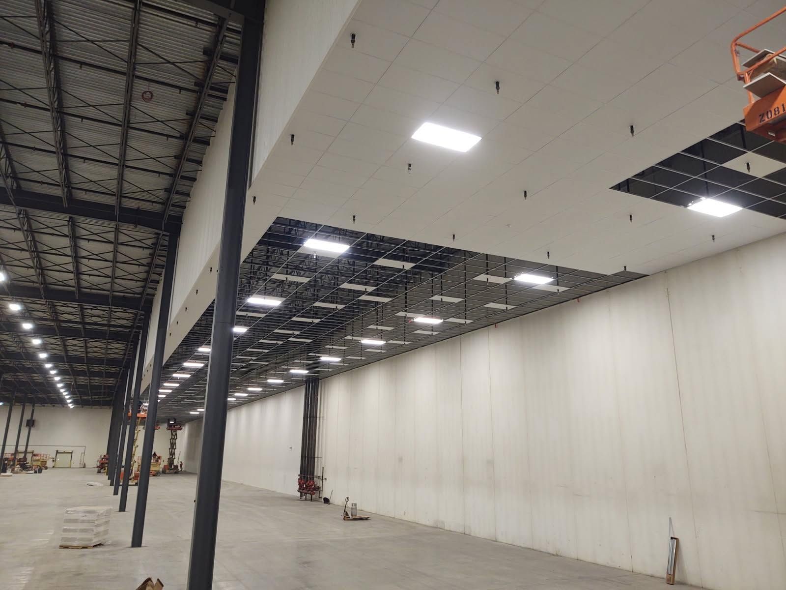 Empty warehouse interior with high ceiling, white walls, and exposed steel beams