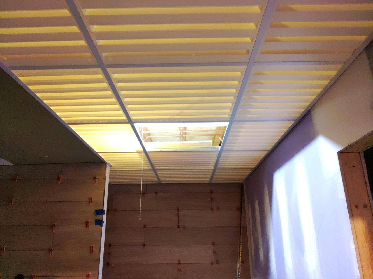 Empty wooden room with a slatted ceiling and bright light coming through a window on the right