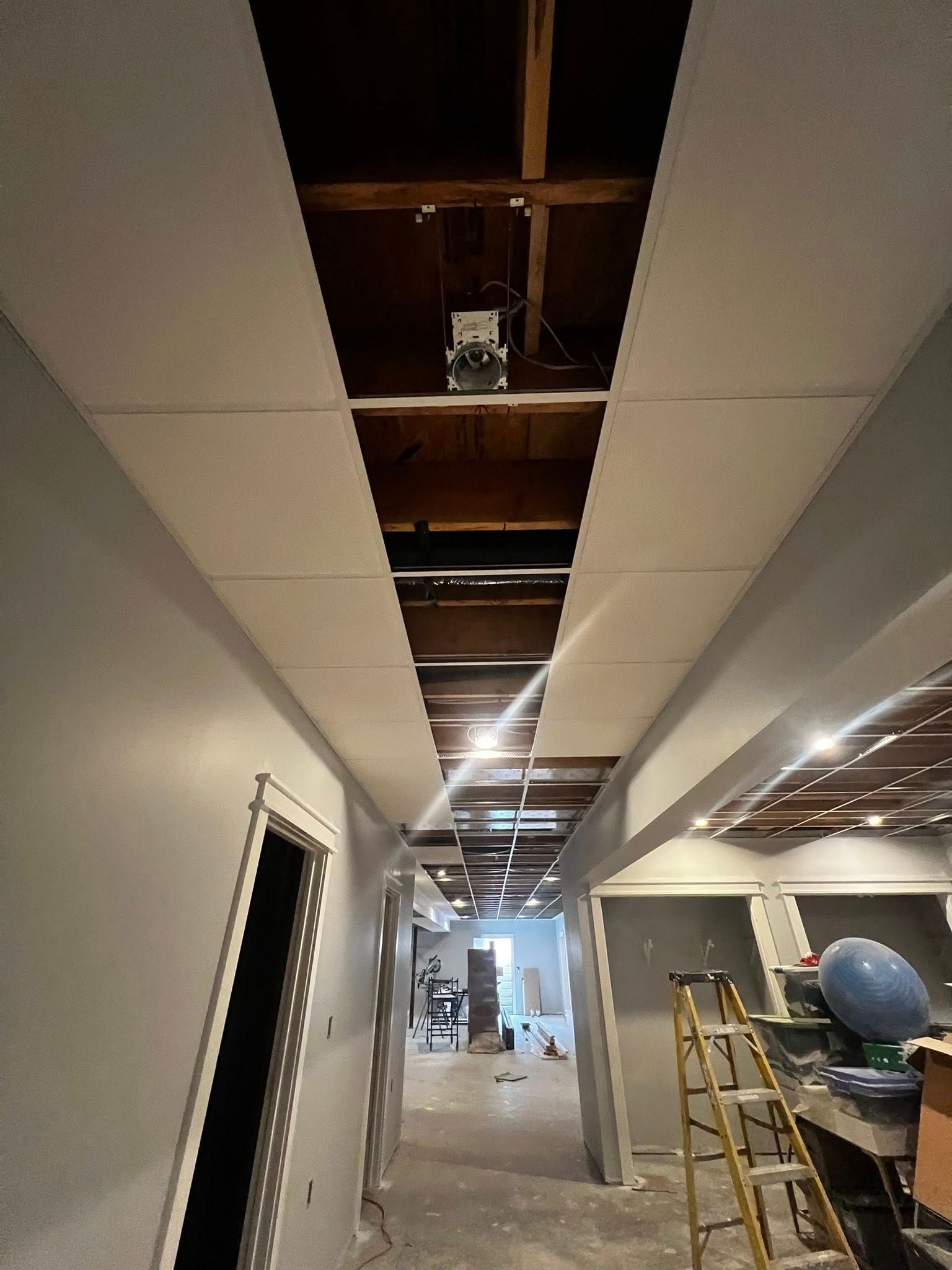 Partially finished hallway with exposed ceiling, ladder, and construction materials.