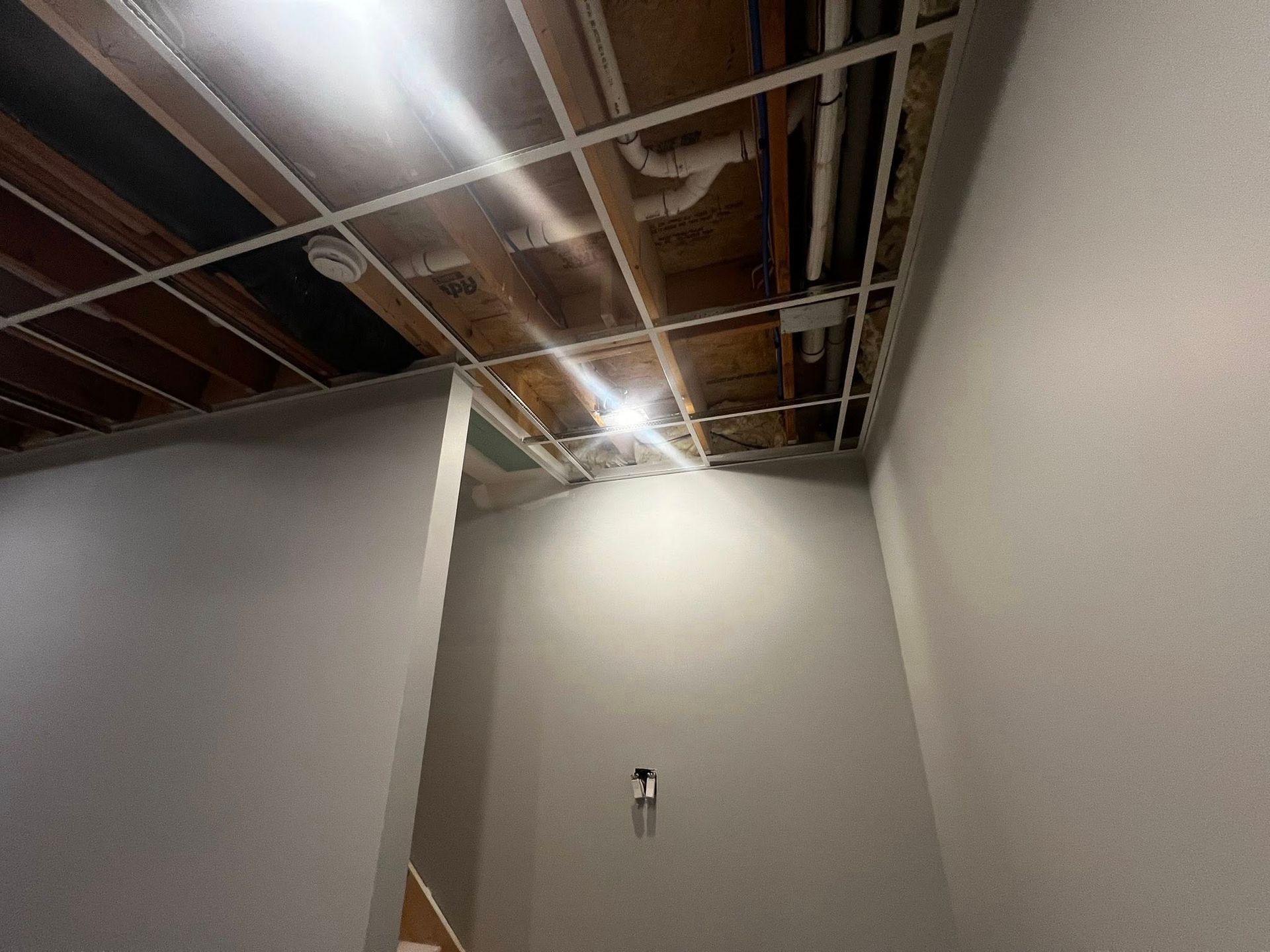 Interior hallway with exposed ceiling beams, bare concrete walls, and a light fixture