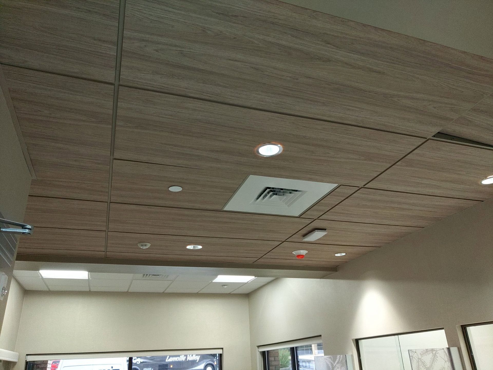Office ceiling with recessed lights, air vents, and beige ceiling tiles above cubicles.