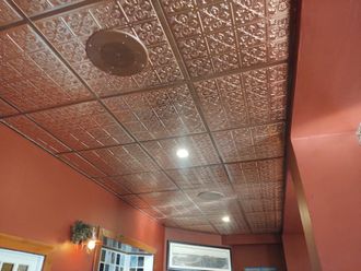 Red hallway with decorative tin ceiling, recessed lights, and a TV screen at the end.