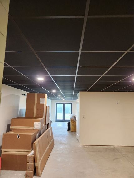 Empty hallway with stacked cardboard boxes and a drop ceiling under construction