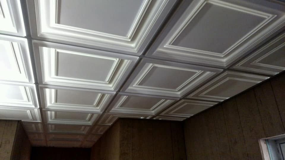 White coffered ceiling panels above dark wood-paneled walls in a room