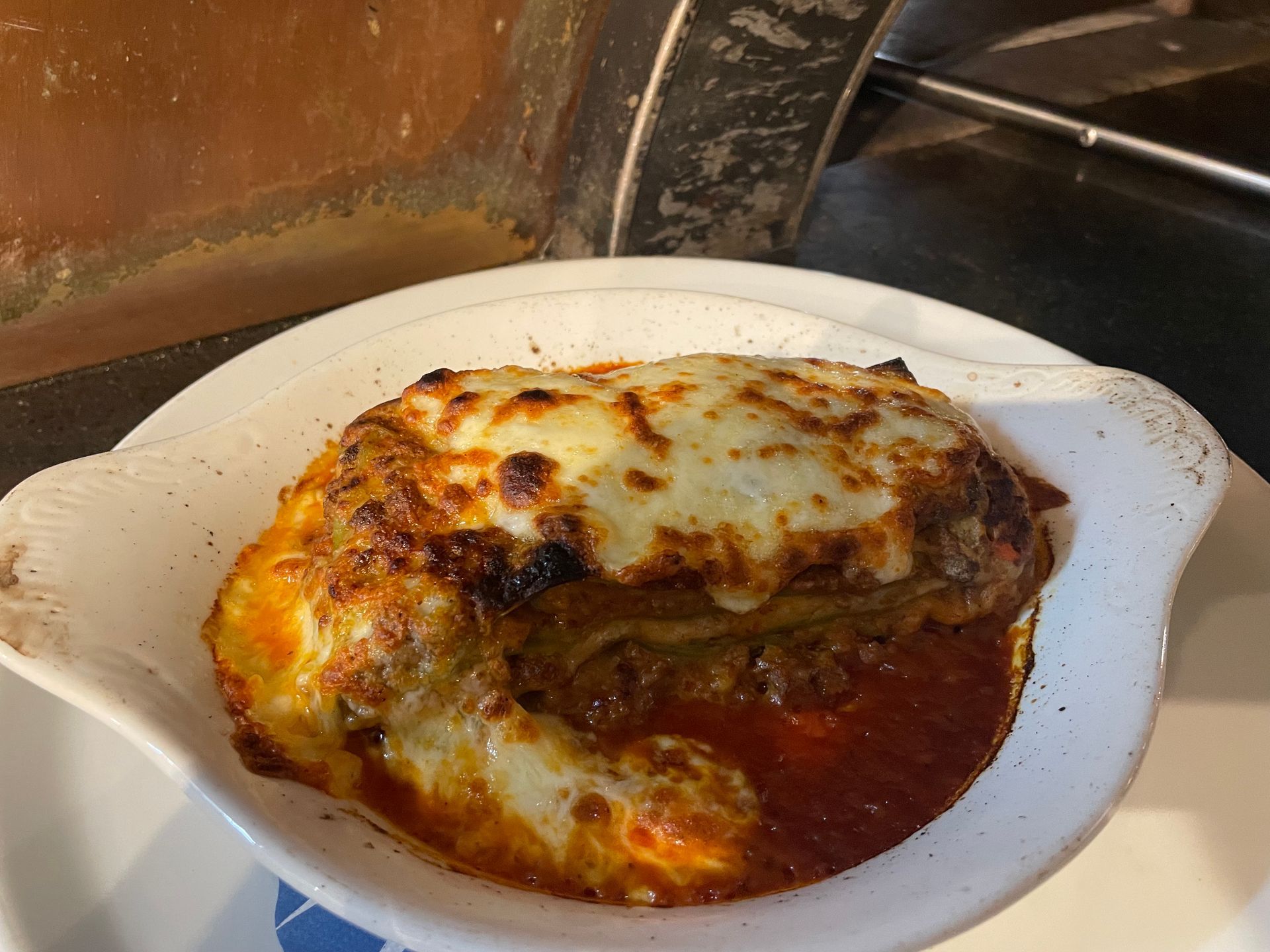 Lasagne in einer weissen Auflaufform, mit geschmolzenem Käse und roter Sosse überbacken.