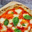 Pizza Margherita auf Holzschieber, mit frischem Basilikum und geschmolzenem Mozzarella.