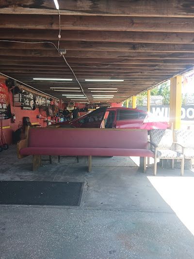 Red couch under a covered garage; tools and red vehicle visible.