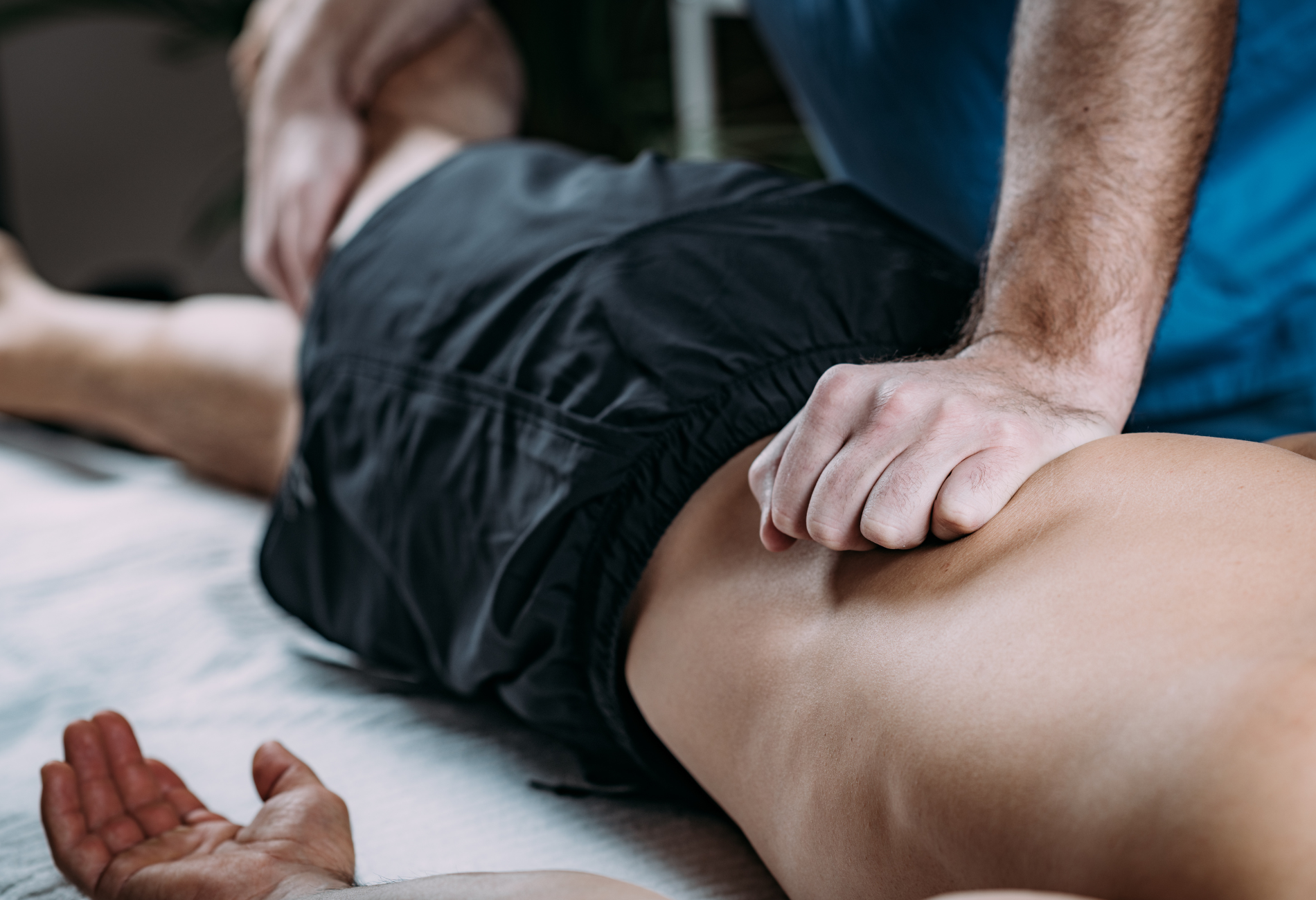 A man is laying on a bed getting a massage from a massage therapist.