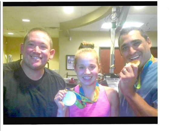 Two men and a girl are posing for a picture with medals around their necks