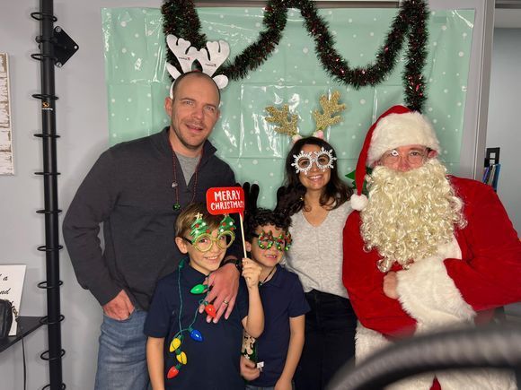 A family is posing for a picture with santa claus in a photo booth.