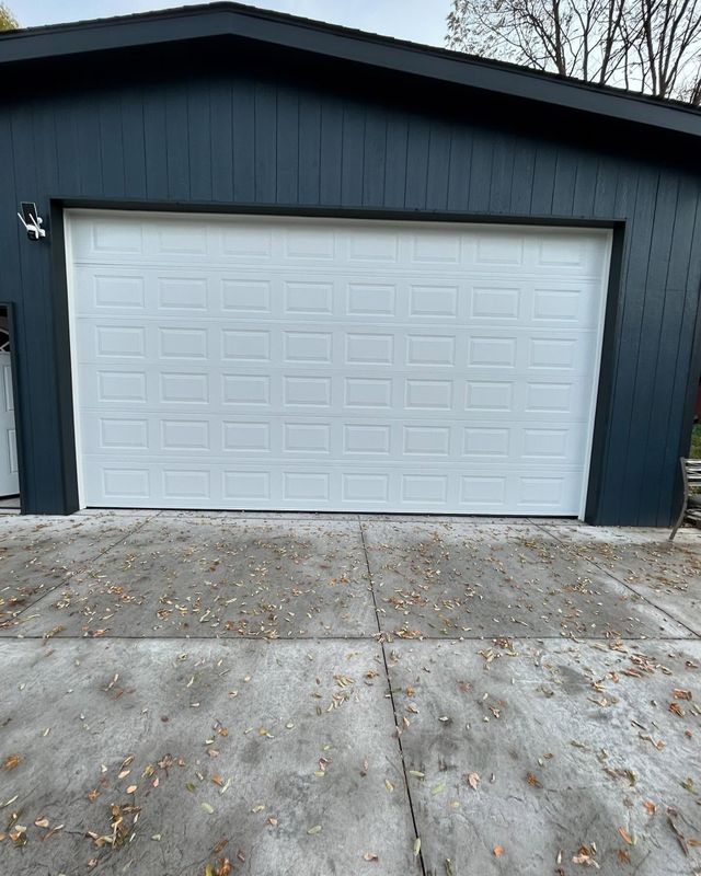Dark blue garage with a white door and concrete driveway in front