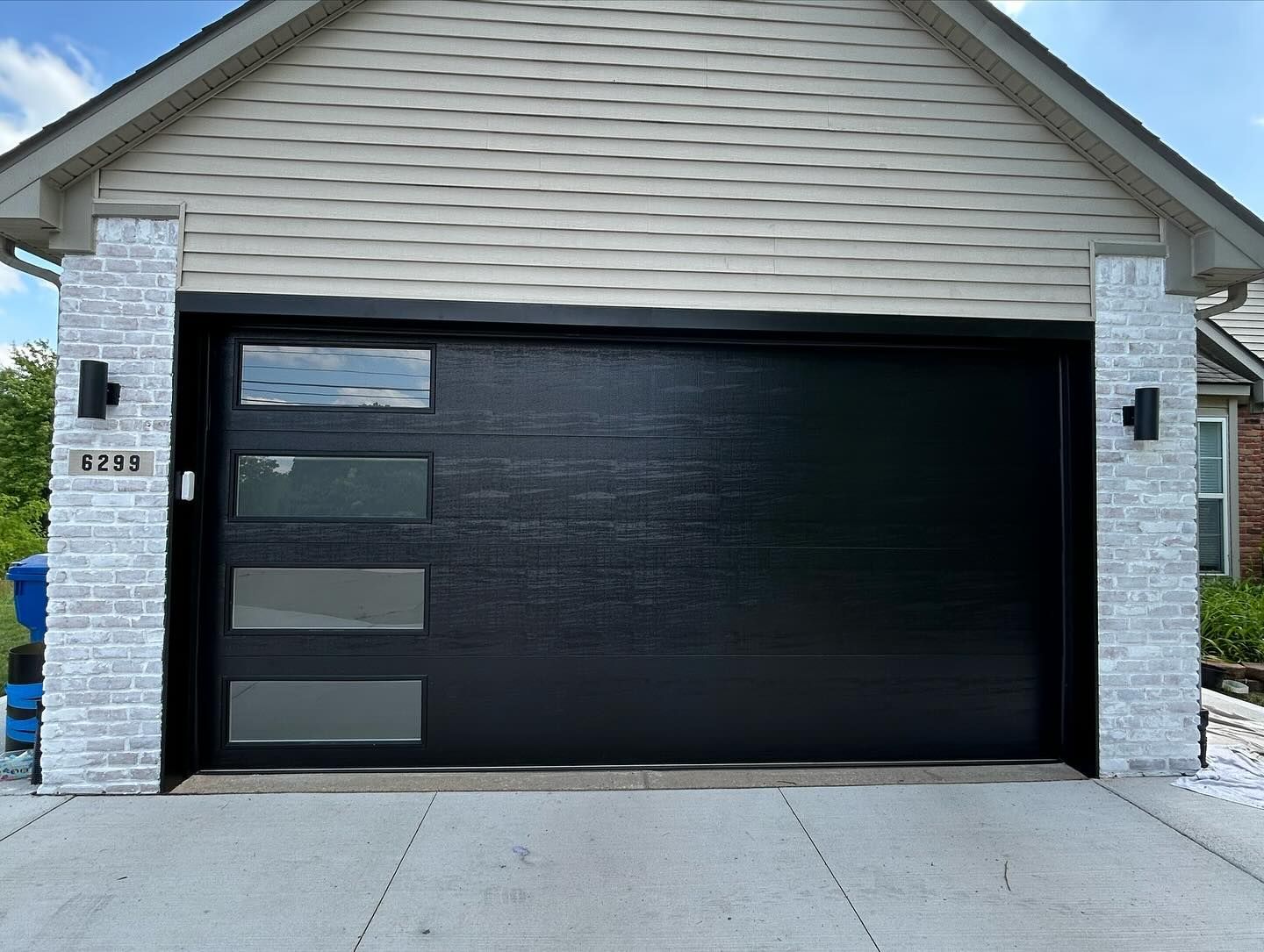 Modern house garage with a large black door and white stone pillars