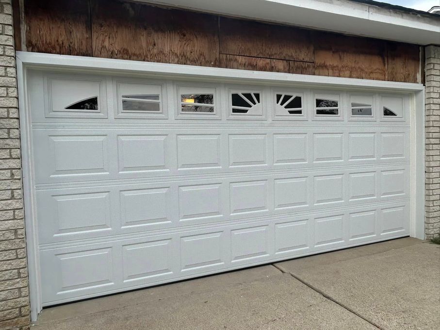 White paneled garage door with small windows under a wood-trimmed roof.