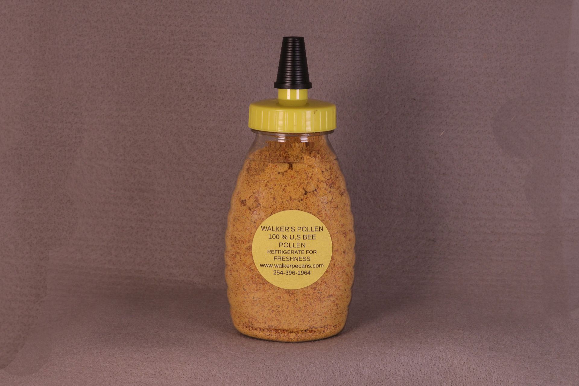 Bottle of amber sauce with yellow cap and black nozzle, labeled on a plain background.