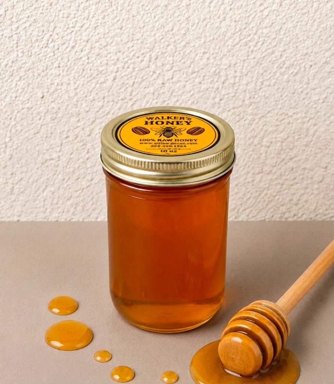 Glass jar of amber honey with a honey dipper and pecans on a wooden table
