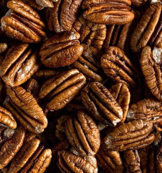 Close-up of glossy brown pecan halves filling the frame