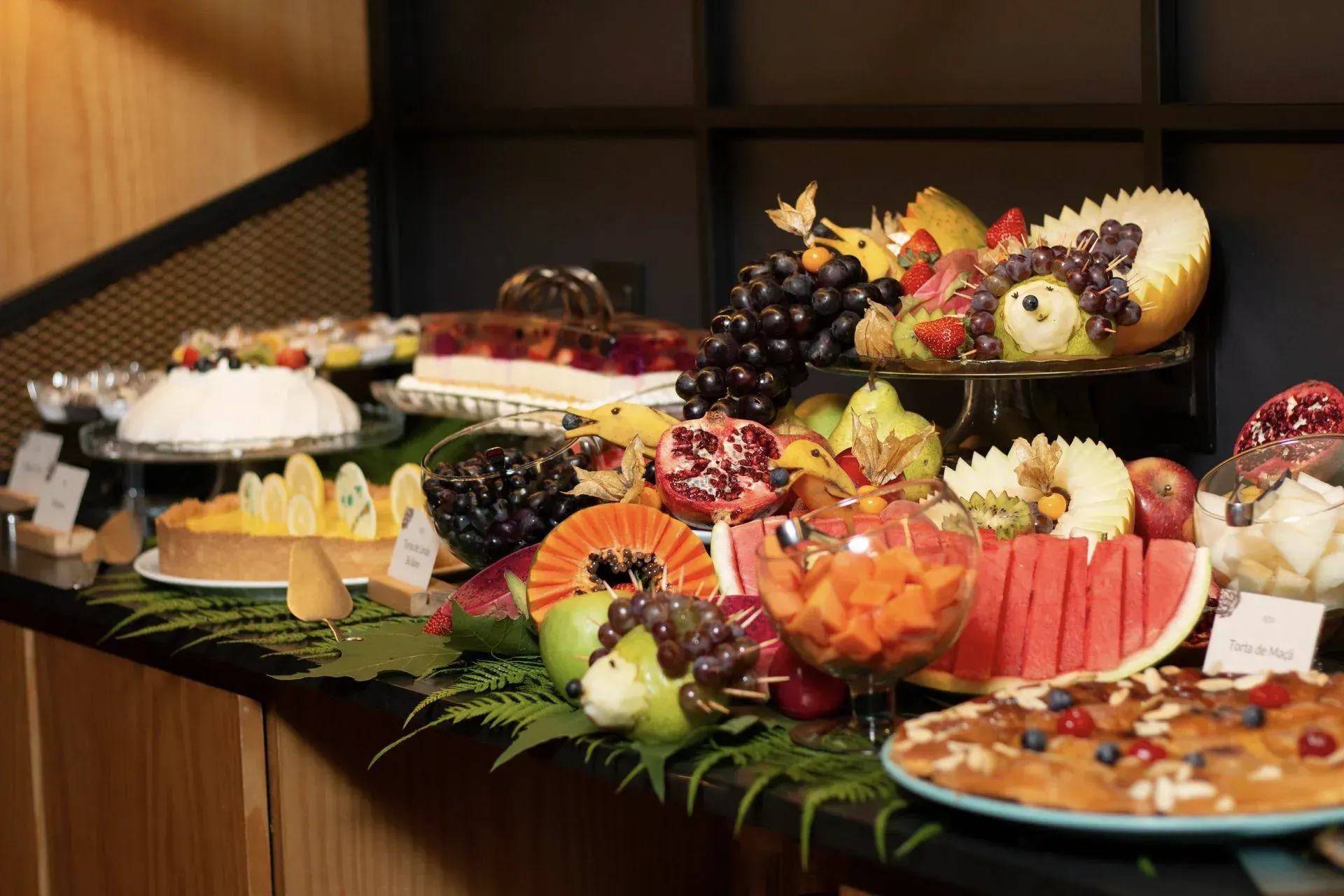 Elegante bufê com uma variedade de sobremesas, pratos de frutas e doces em uma mesa decorada.