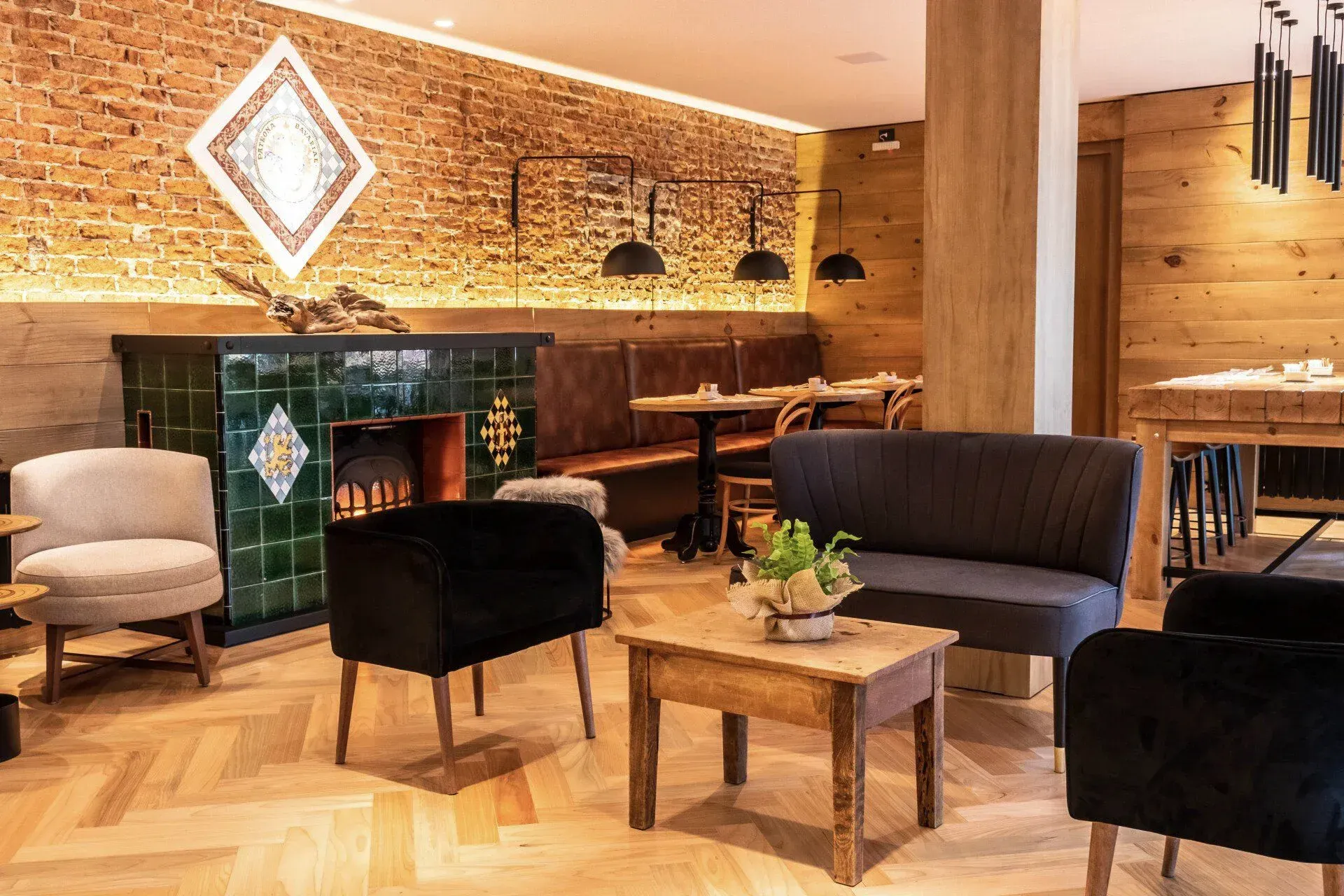 Sala de estar moderna e aconchegante com parede de tijolos, luminárias pendentes, sofás e pequenas mesas de madeira.