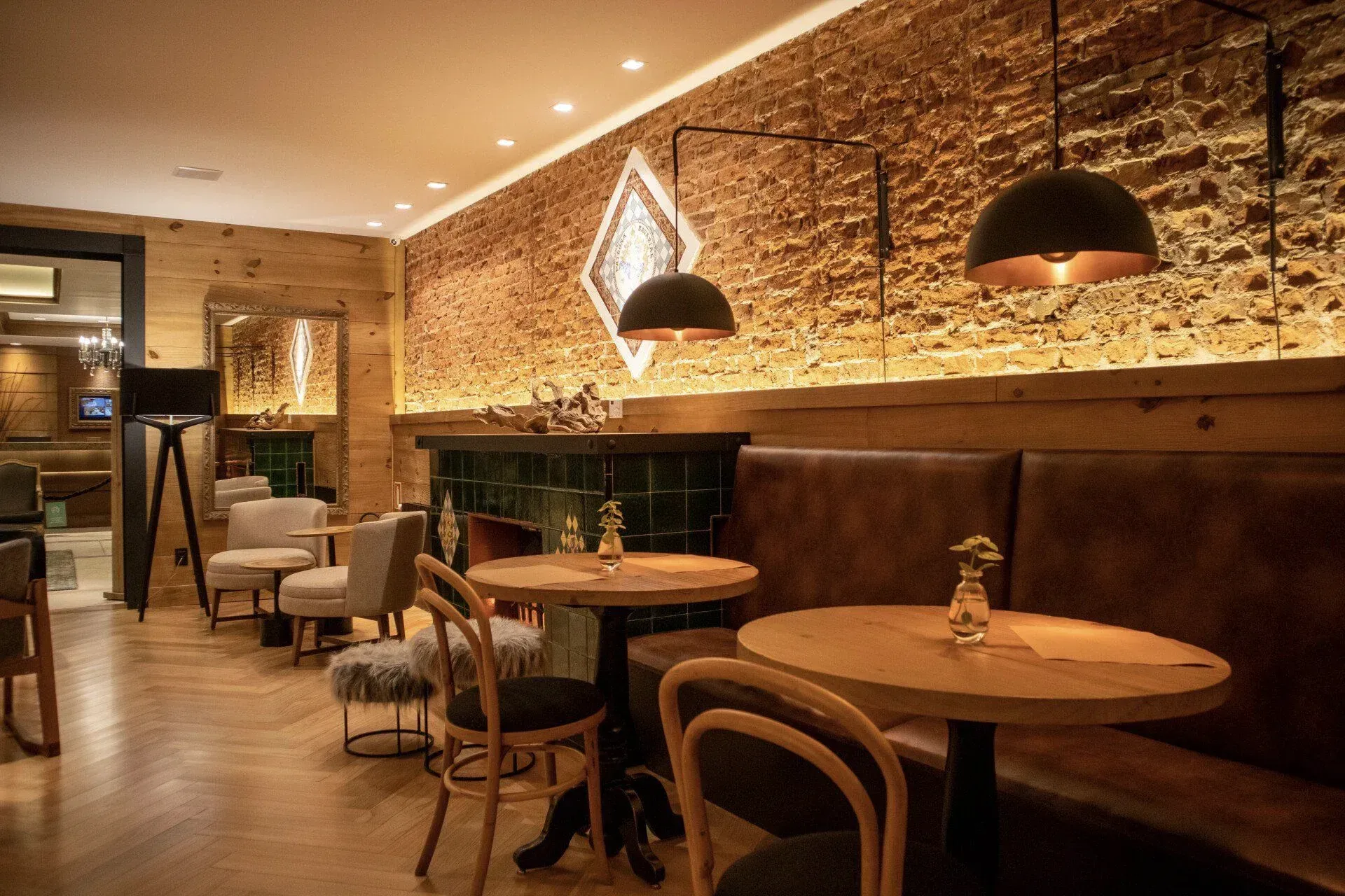 Interior de café moderno e aconchegante com iluminação quente, mesas de madeira, paredes de tijolos e luminárias pendentes.