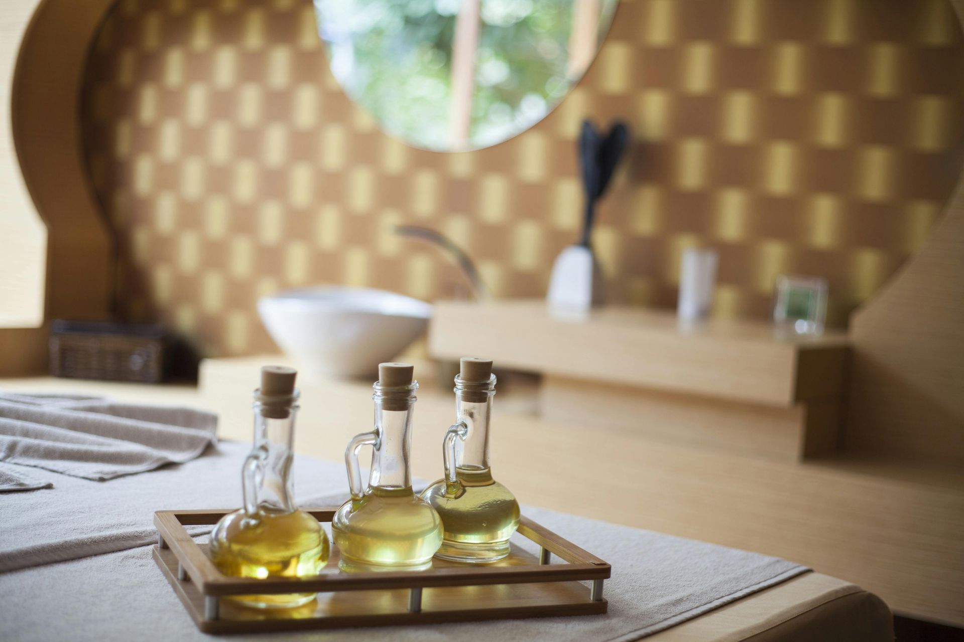 Bandeja com pequenos frascos de vidro contendo óleo amarelo sobre uma mesa em uma sala com ambiente de spa.