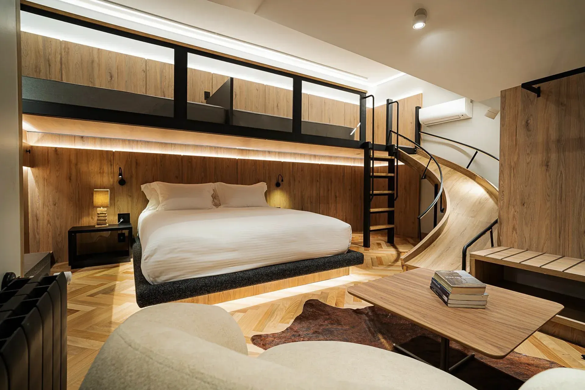 Quarto moderno em estilo loft com cama suspensa de madeira, roupa de cama branca aconchegante, escada e iluminação ambiente acolhedora.