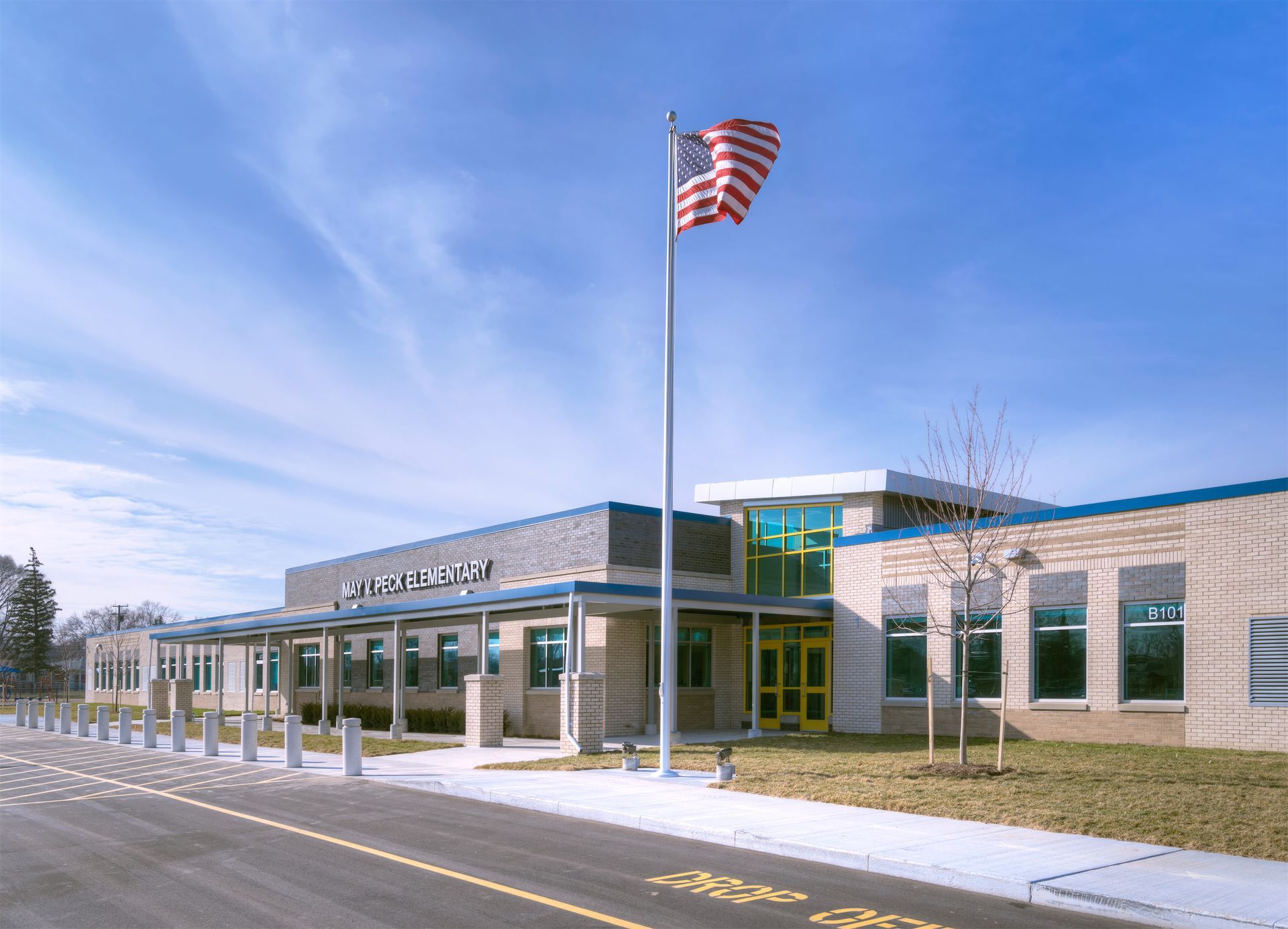 School building with American flag waving; blue sky.