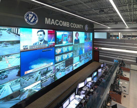 Macomb County emergency operations center with many screens displaying live feeds and information.