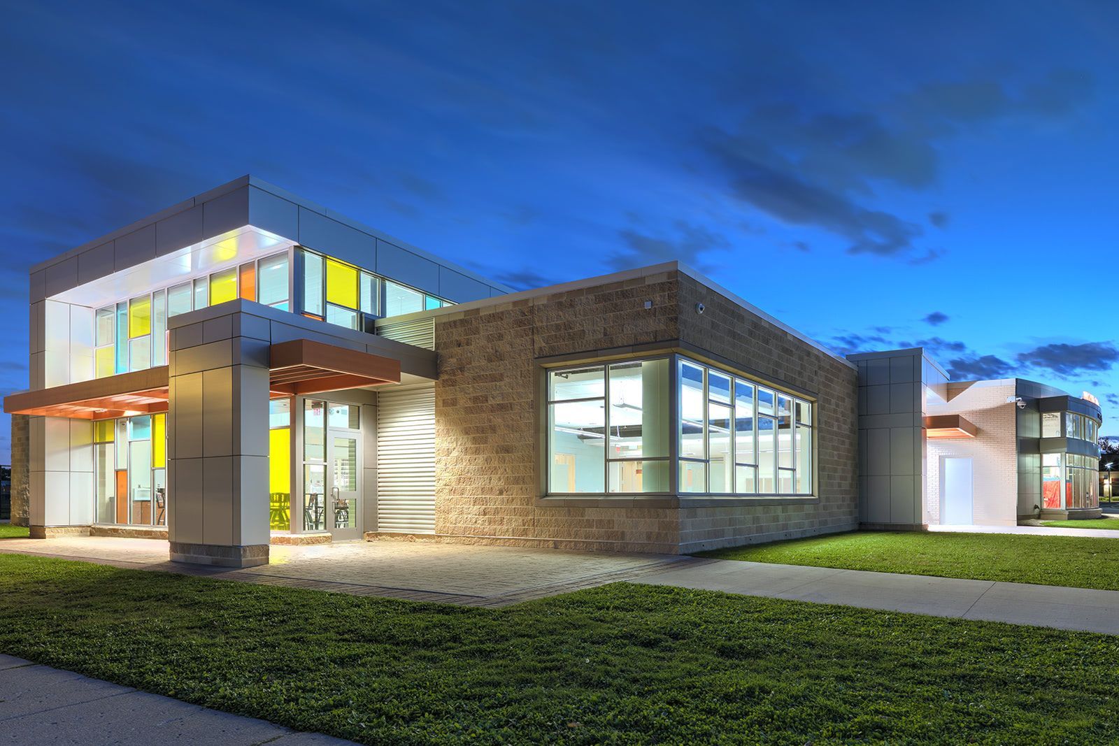 Modern building with stone and metallic accents, colorful windows, and a blue sky.