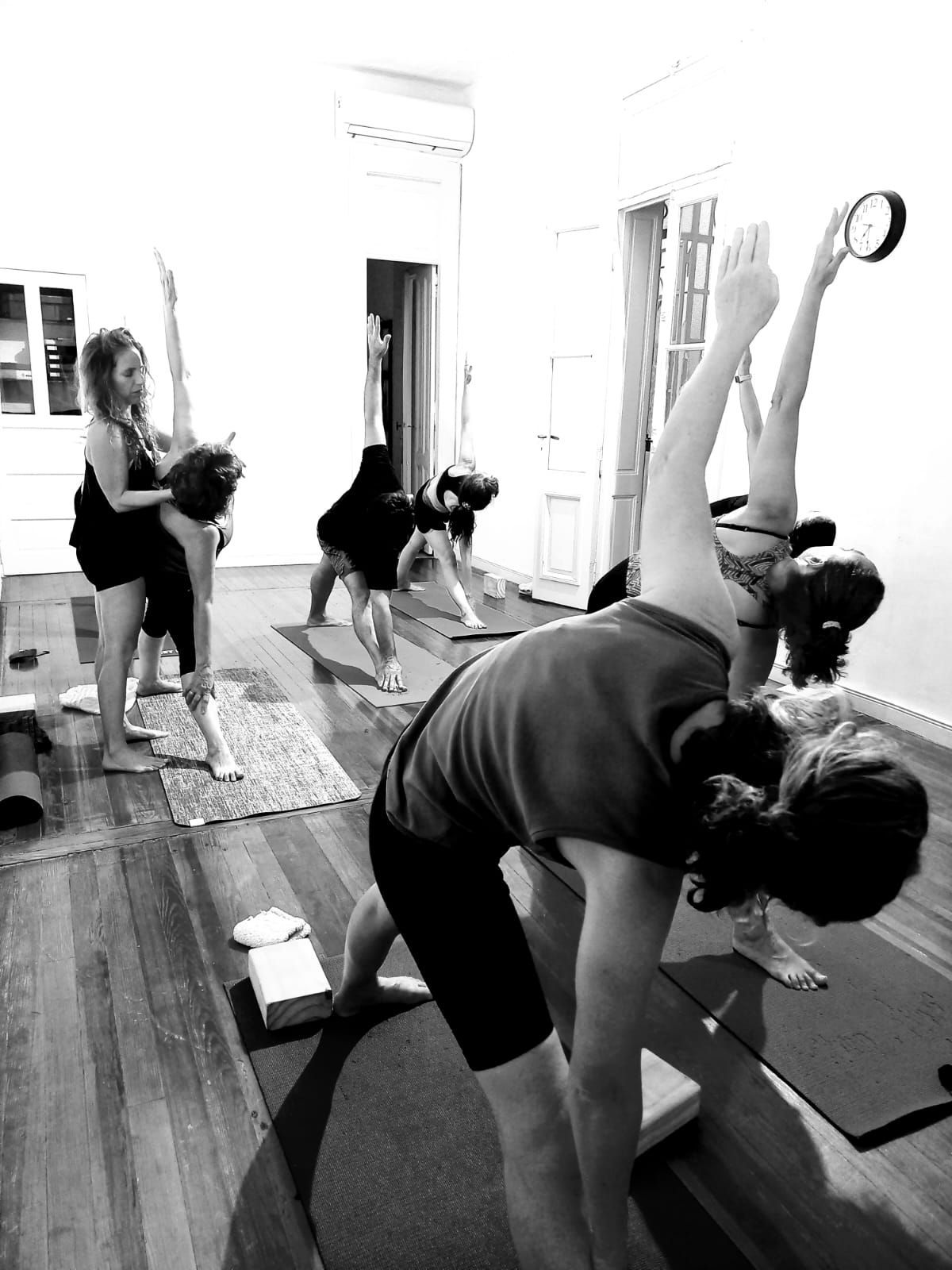 Personas haciendo una clase de yoga con estiramientos laterales sobre colchonetas en un estudio.